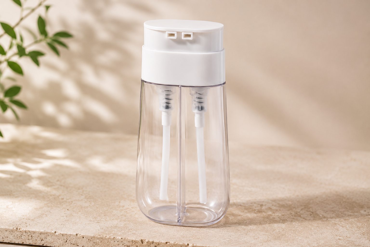 Envase cosmético doble cámara transparente con doble bomba, dos salidas y tubos de aspiración visibles.