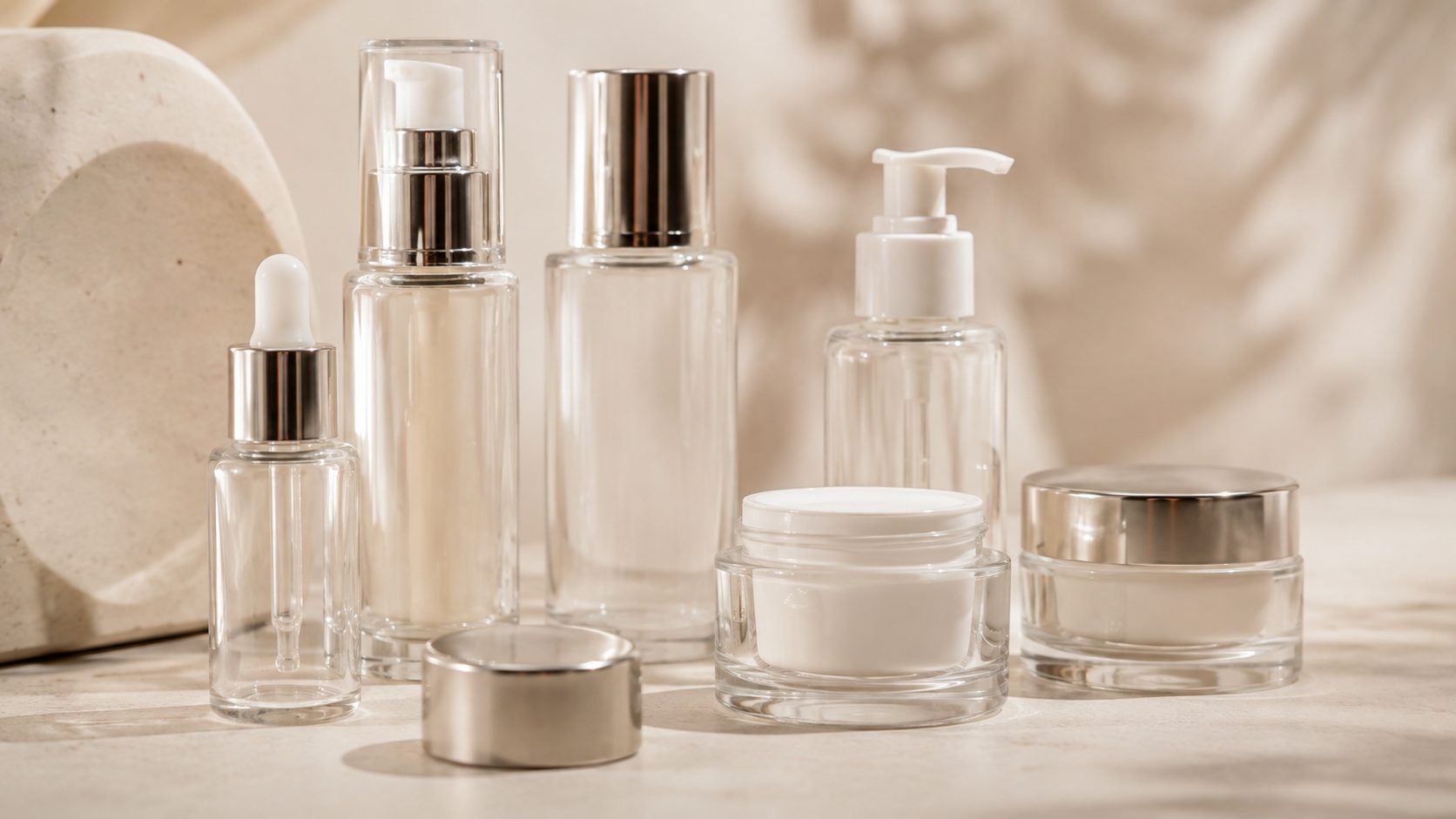 Envases cosméticos de vidrio con cierres y bombas para revisar tolerancias dimensionales antes de producir.