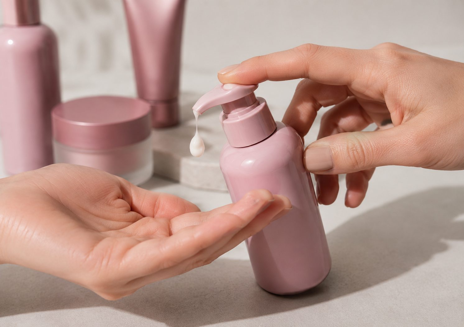 Dosis por pulsación en bomba cosmética rosa dispensando crema sobre la mano.